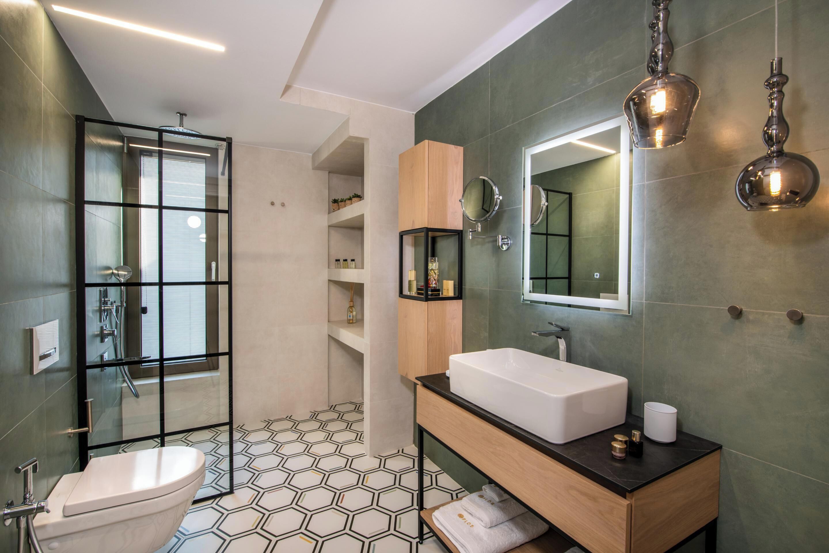 Une salle de bain moderne dotée d’une douche à parois de verre, de toilettes sur pied, d’un meuble-lavabo en bois et d’un grand miroir.