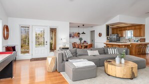 A spacious living room with a grey sectional sofa, a wooden coffee table, and a dining area with a wooden table and chairs. - New! Big Sky Cabin at Yosemite w/ VIEWS, hot tub, firepit, and more! (Oakhurst)
