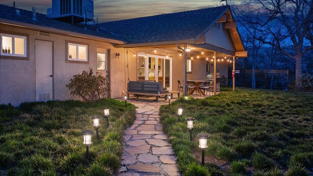 A house with a stone pathway leading to a covered patio area with outdoor seating. - New! Big Sky Cabin at Yosemite w/ VIEWS, hot tub, firepit, and more! (Oakhurst)