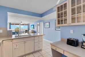 A kitchen with a large island, a toaster, and a blender on the counter. There are cabinets with glass doors and a window with a view. - Waterfront Dock Pool Downtown Near Duval Pet (Key West)