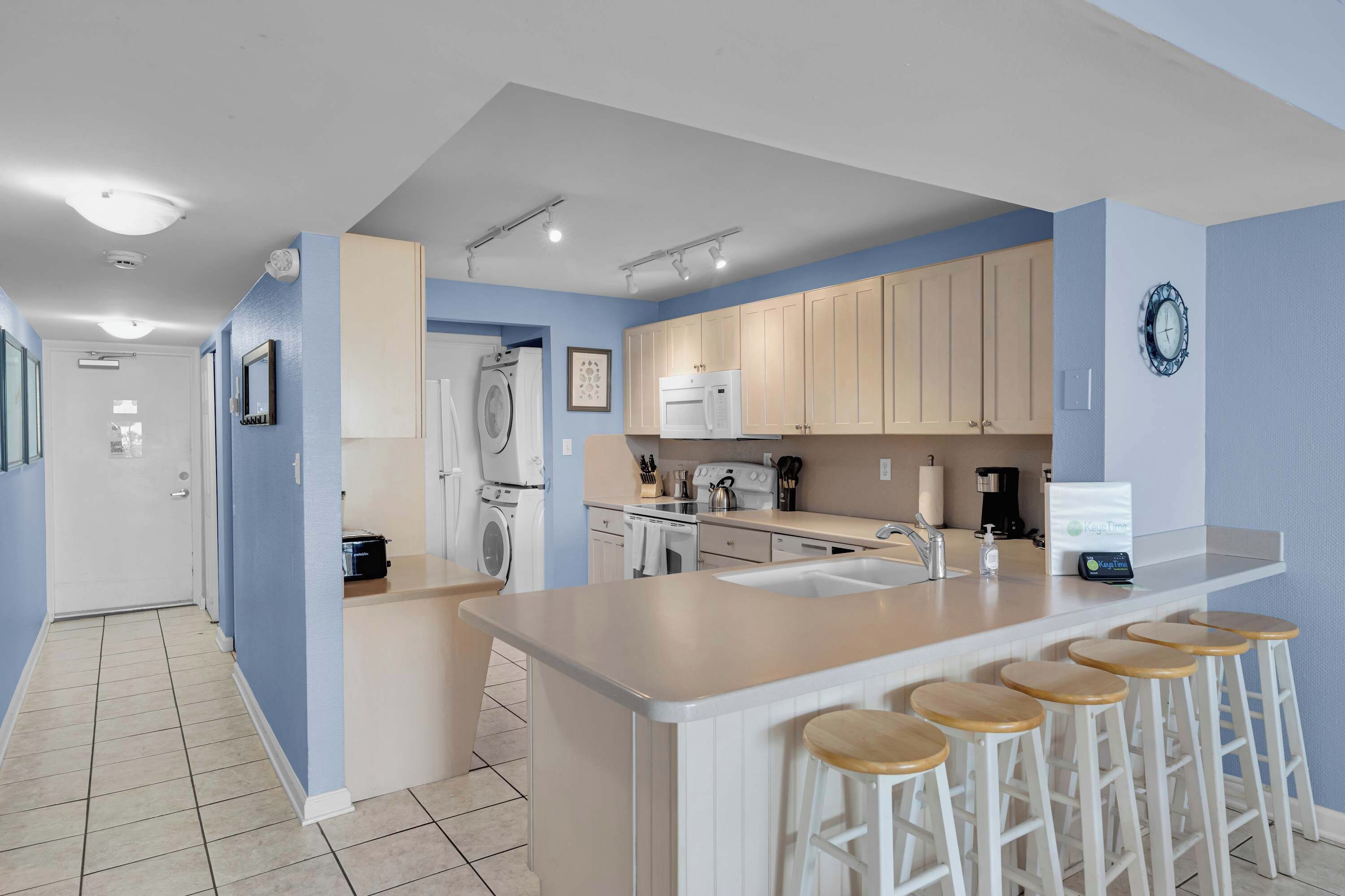 Une cuisine moderne avec un îlot central, des tabourets de bar et des murs bleu clair.