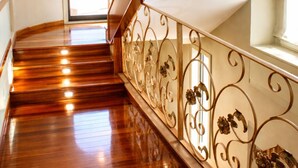 Una escalera de madera con barandillas de metal decoradas, que conduce a un arco de entrada.