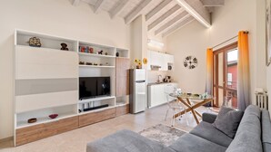 A modern living room with a sofa, TV, and built-in shelving. - Garda Girasole quiet three-room apartment near the lake with private parking (Desenzano del Garda)