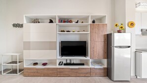 A modern living room with a flat-screen TV, wooden cabinets, and a built-in refrigerator. - Garda Girasole quiet three-room apartment near the lake with private parking (Desenzano del Garda)