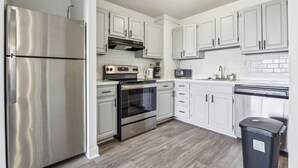 A modern kitchen with stainless steel appliances, white cabinetry, and a wood floor. - Legacy at Imperial Village 1014 I 2 Bed 2 Bath (Ric hmond)