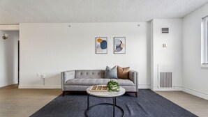 Un saló modern amb un sofà gris, una taula de centre rodona i dues obres d'art abstractes penjades a la paret.