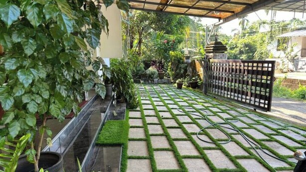 Un camí al jardí amb dibuix de reixa, envoltat de plantes en testos i una tanca de fusta.