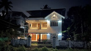 Una casa de dues plantes amb un balcó, una porta d'entrada i un vestíbul ben il·luminat.