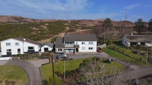 Una zona residencial con casas, un coche y una colina al fondo.