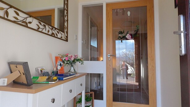 Un área de recepción con un mostrador de madera, un jarrón con flores y una puerta de vidrio que da al exterior.