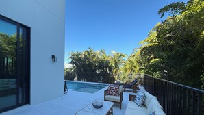 Une terrasse extérieure moderne, dotée d’une piscine, d’un espace salon et d’une végétation luxuriante.
