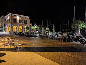 A waterfront restaurant with outdoor seating, a paved area, and a view of the marina. - Villa Rosa Apartment (Gargnano)
