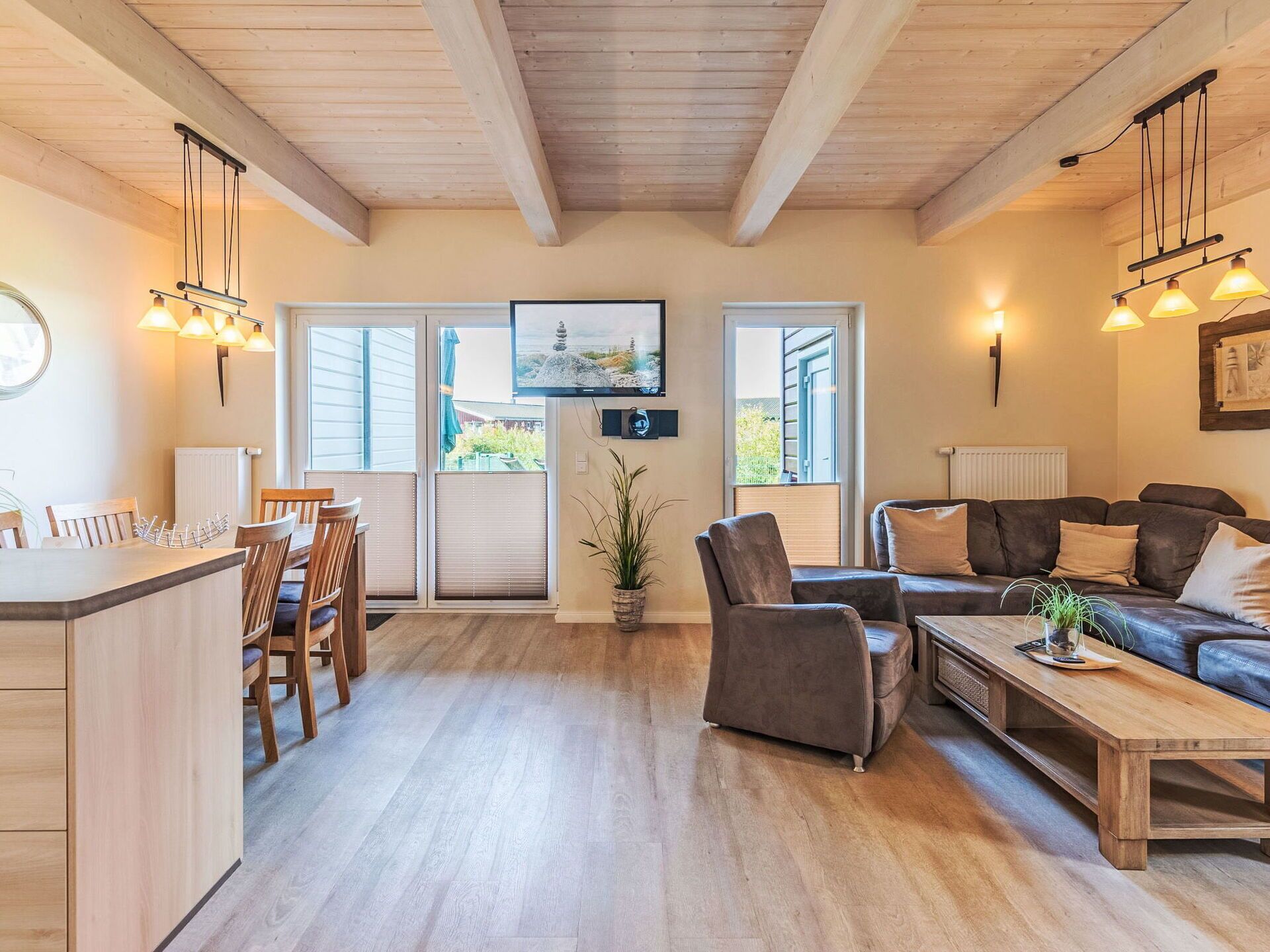 A spacious living area with a wooden floor, a sofa, a coffee table, and a dining area with chairs and a table.
