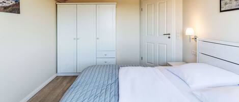 A bedroom with a bed, a wardrobe, and a door.
