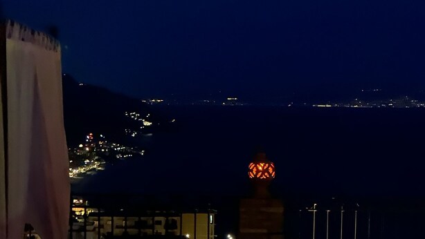 A pool area with a view of a cityscape at night. - Isoco Terrace (Taormina)