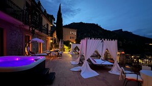 An outdoor patio area with a hot tub, lounge chairs, and a canopy structure. - Isoco Terrace (Taormina)
