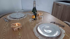 Uma mesa de jantar de madeira posta com pratos, copos, uma garrafa de vinho e velas.