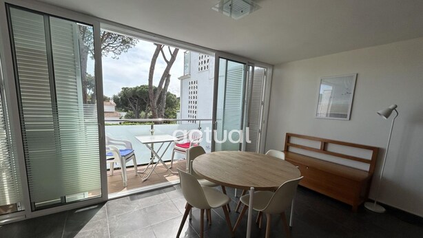 A modern room with a round table and chairs, a bench, and a view through large glass doors to an outdoor area with a pool and trees. - Charming apartment with pool near the beach in Platja d'Aro (Platja d'Aro)