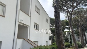 A white multi-story building with a staircase leading to the entrance, surrounded by trees and a car parked on the side. - Charming apartment with pool near the beach in Platja d'Aro (Platja d'Aro)