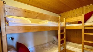 Una camera con letti a castello, pareti e soffitto in legno.