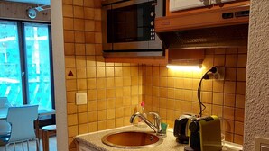 A kitchen with a sink, a microwave, and a toaster. There is a window with a view of the outside. - Cozy apartment with balcony and parking in Chamonix, near the center (Chamonix-Mont-Blanc)