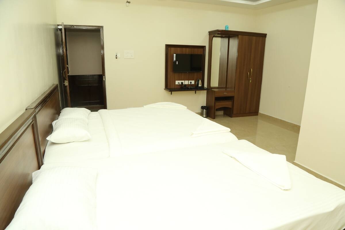 Habitación de hotel con cama, armario, espejo y televisión.
