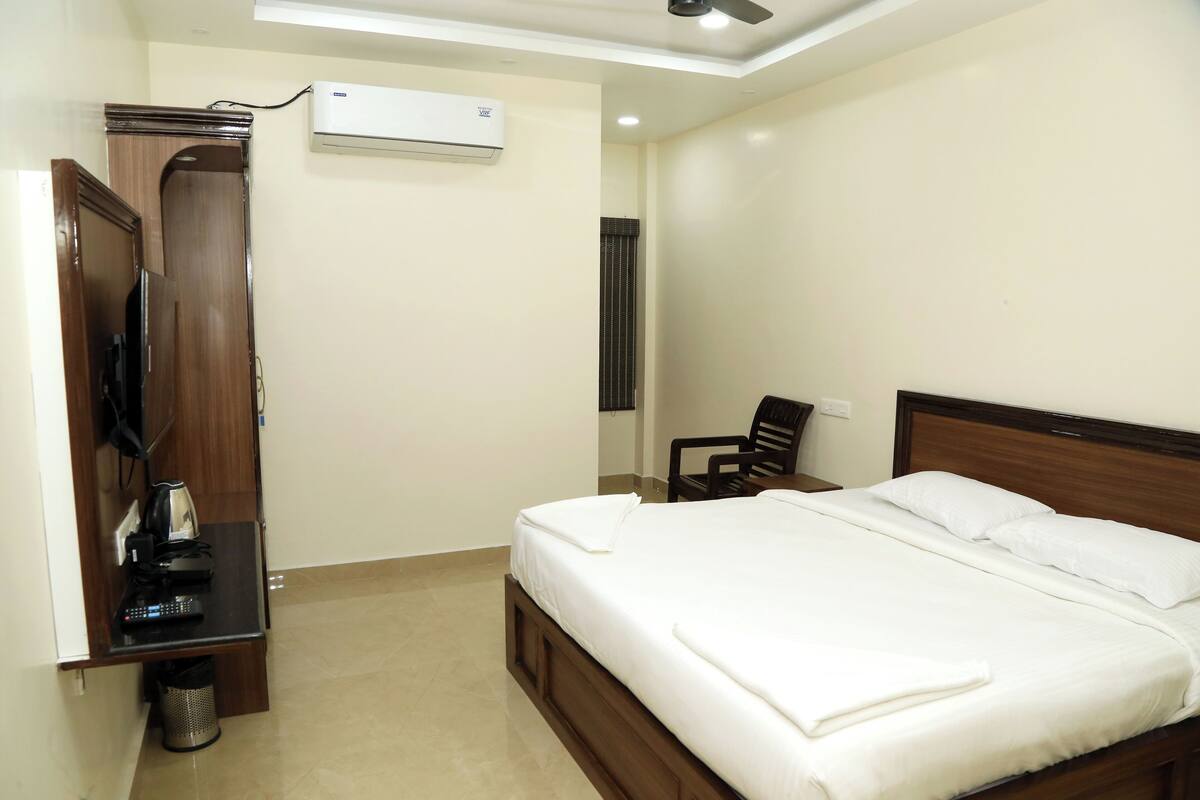 Una habitación de hotel con una cama, un escritorio con silla, aire acondicionado y un armario.