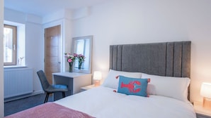 Hotellihuone, jossa on sänky, työpöytä, tuoli, peili ja ikkuna.