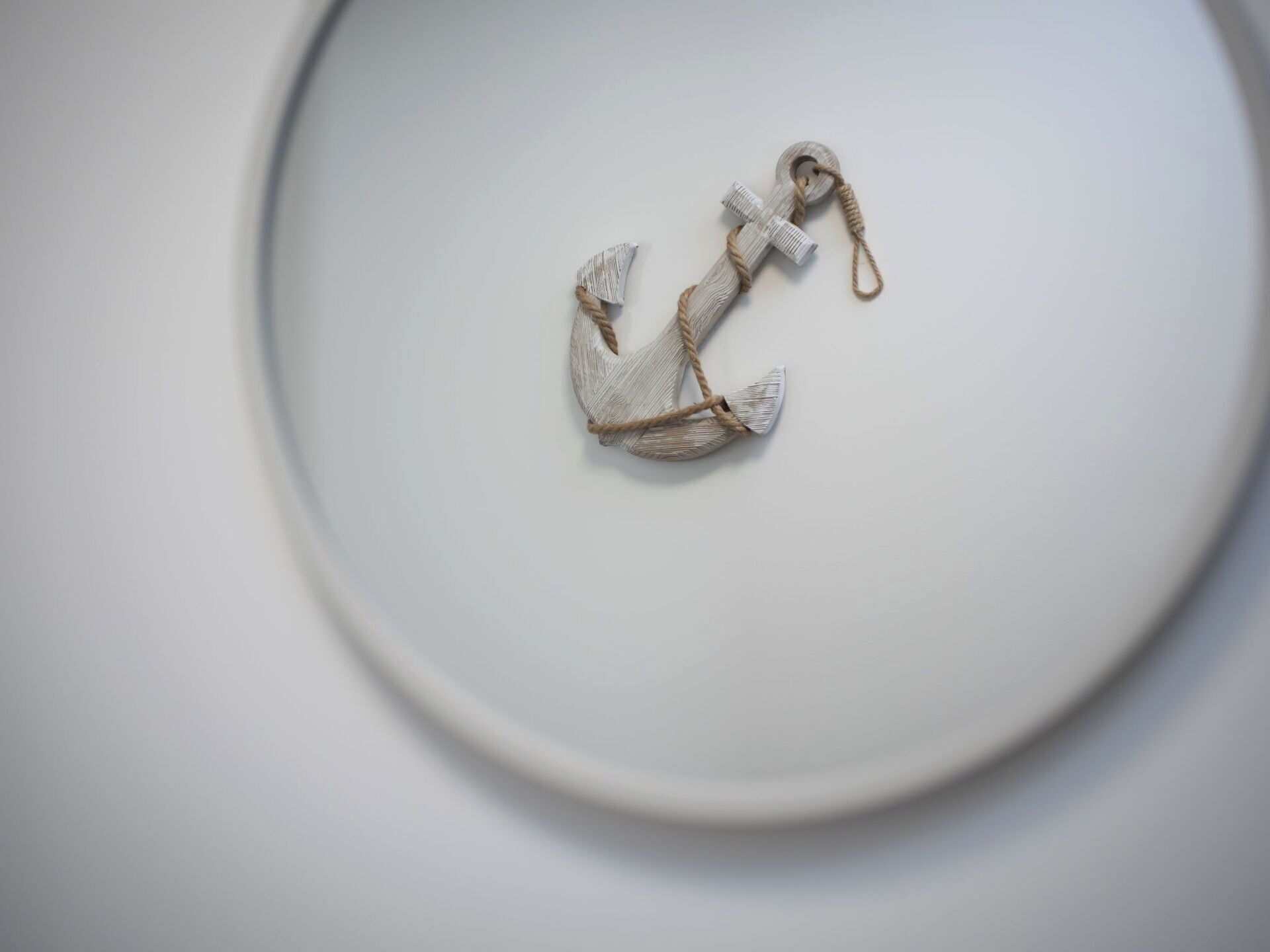 A white plate with a white anchor-shaped object.