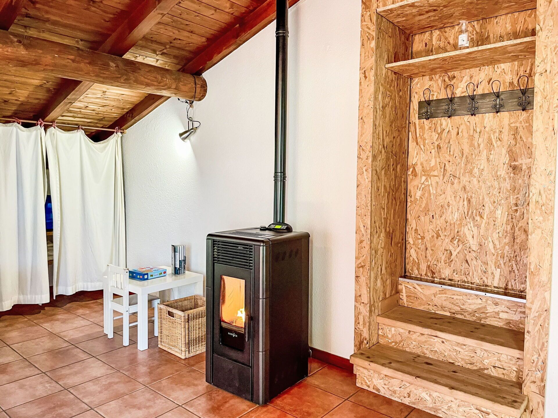A cozy room with a wood-burning stove, a white chair, and a small table.