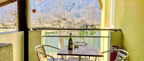 Un patio con una mesa y sillas, una botella de vino y vistas a la montaña.