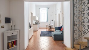 Eine moderne Wohnung mit Küche, Essbereich und Wohnzimmer. Eine Treppe mit Metallgeländer und Blick ins Freie.