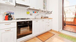 Cozinha moderna com armários brancos, fogão a gás e forno embutido.