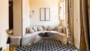 Ein Eckzimmer mit einer Couch, einem kleinen runden Tisch und einem gemusterten Boden.