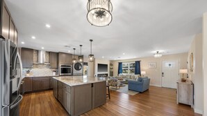 Una cocina moderna con una isla central, electrodomésticos de acero inoxidable y una zona de comedor con un sofá azul.