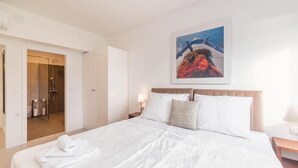Habitación de hotel con una cama grande, baño con ducha y un cuadro enmarcado en la pared.