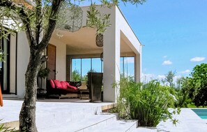 Een modern huis met een terras, een rode bank en een zwembad.