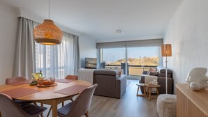 Un soggiorno moderno con zona pranzo, ampie finestre e vista sull'esterno.