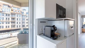 Una cucina compatta con macchina da caffè, forno a microonde e un piccolo ripiano in legno.