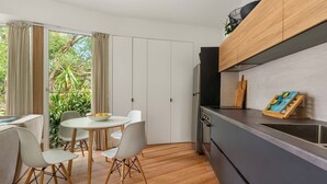 A compact kitchen with a dining area, a refrigerator, and a wooden cabinet. - Sea Glass Studio Inverloch by the sea (Inverloch)