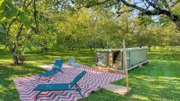 An outdoor setting with a picnic table, chairs, and a small wooden structure.