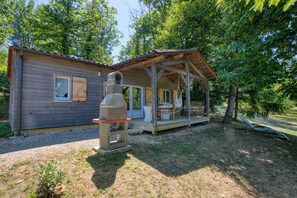 Ein rustikales Blockhaus mit Veranda, Steinofen und einem kleinen Garten.