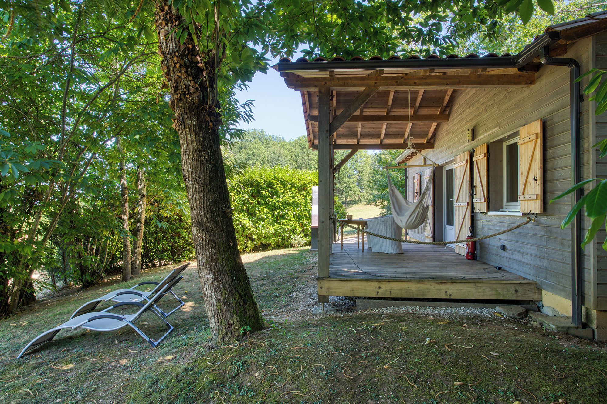 Une cabane en bois dotée d’un porche couvert, d’un hamac et d’un extincteur.