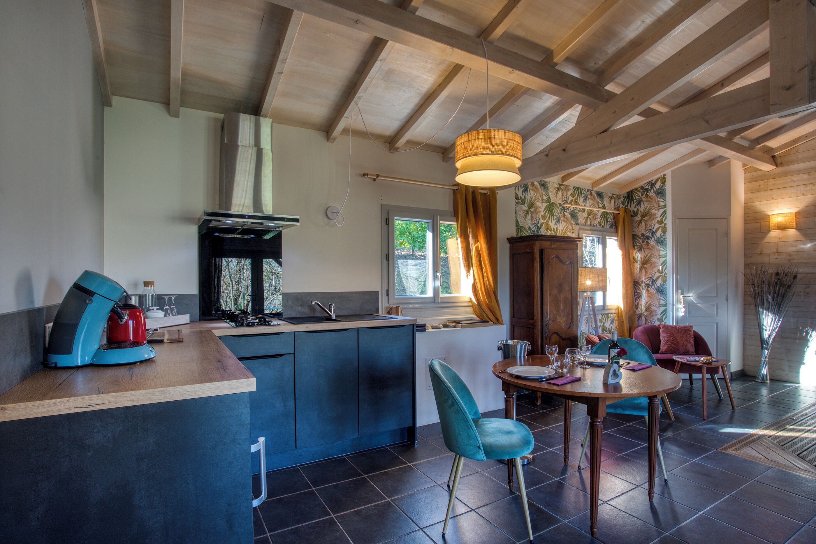 A modern kitchen with a central island, a dining area with two chairs, and a wooden ceiling.