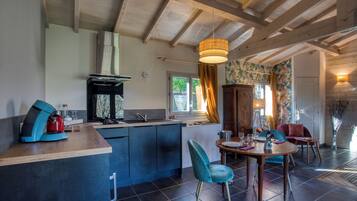 A modern kitchen with a central island, a dining area with two chairs, and a wooden ceiling.