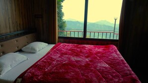 Una camera da letto con un letto, una testiera in legno, una finestra vista montagne e un cornicione del balcone.