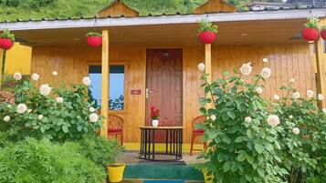 A wooden building with a porch, a door, and a small table with chairs.