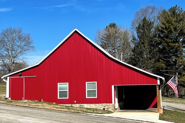 Une grange rouge avec une porte de garage, une petite fenêtre et un drapeau américain.