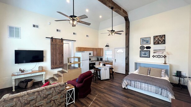 A spacious living area with a large bed, a sofa, a TV, and a kitchen in the background. - Charming historic barn in New Market with WiFi and AC (New Market)