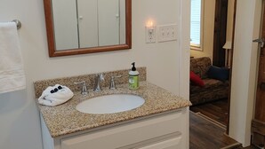 A bathroom with a white vanity, a sink, a mirror with an ornate frame, a towel, and a bottle of hand soap. - Charming historic barn in New Market with WiFi and AC (New Market)